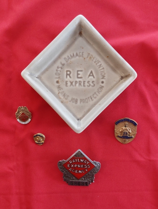 Family keepsakes of Jimmy Fitzgerald's family - small ceramic tray with hat badge in front and flanked left and right by safe driving pins.